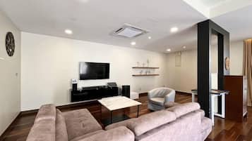 A modern living room with a sectional sofa, a flat-screen TV, a coffee table, and a small side table.