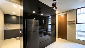 Eine moderne Küche mit einem schwarzen Kühlschrank, einer Holztür und einem Deckenventilator.