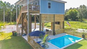 A two-story house with a pool, wooden deck, and a flag. - Beautiful New Home Near Beach with Pool Sleeps 6 (Pass Christian)