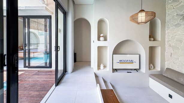 A modern interior with a pool view, a stone wall, and a mounted sign. - Athaya Canggu Villas by Nagisa Bali (Canggu)