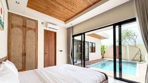 A bedroom with a large bed, wooden ceiling, and a sliding glass door leading to a swimming pool. - Athaya Canggu Villas by Nagisa Bali (Canggu)