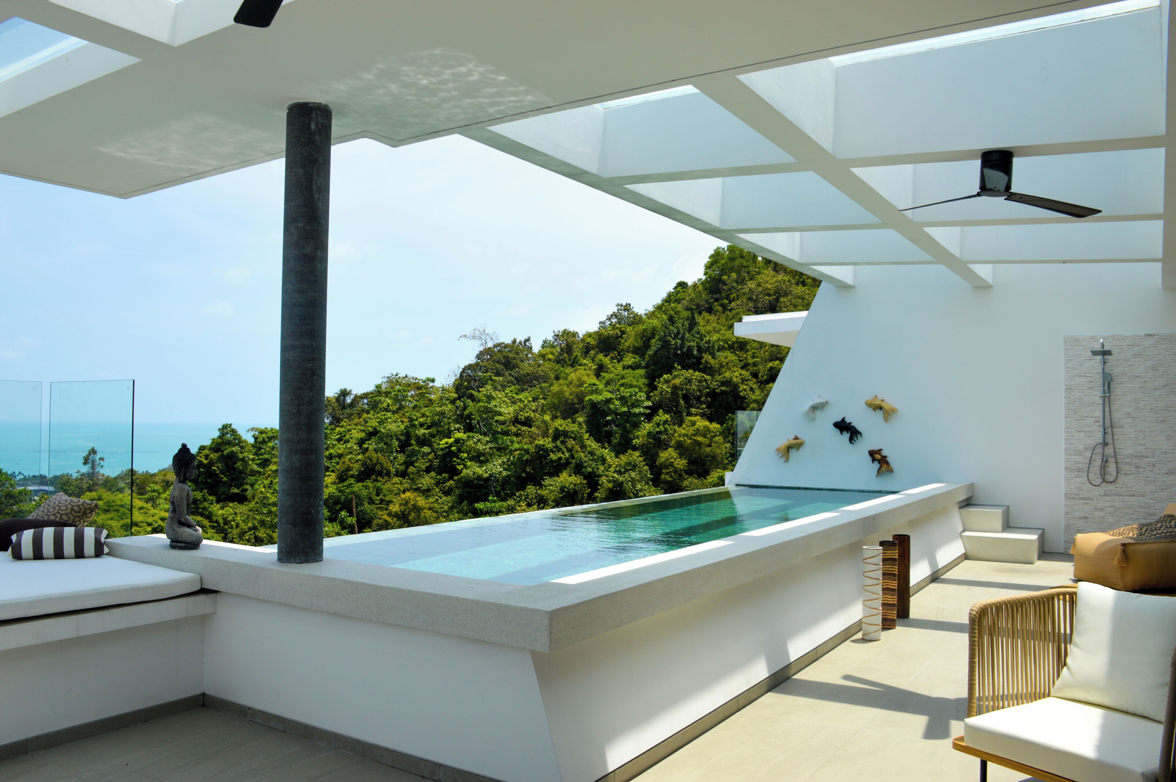 Una piscina infinita en la azotea con vistas claras al océano y abundante vegetación.