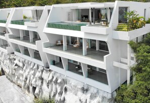 A modern multi-story building with a pool, balconies, and indoor seating areas. - Golden Lotus Villas (Koh Samui)