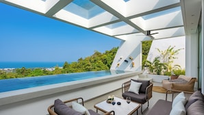 A modern outdoor lounge with a pool, seating, and a view of the ocean. - Golden Lotus Villas (Koh Samui)