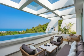 A modern outdoor lounge with a pool, seating, and a view of the ocean. - Golden Lotus Villas (Koh Samui)
