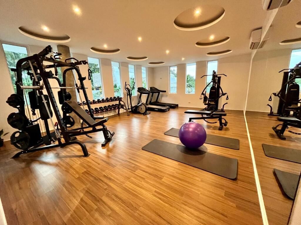 Une salle de sport équipée de machines de cardio, de poids libres et de tapis de sol pour les exercices.