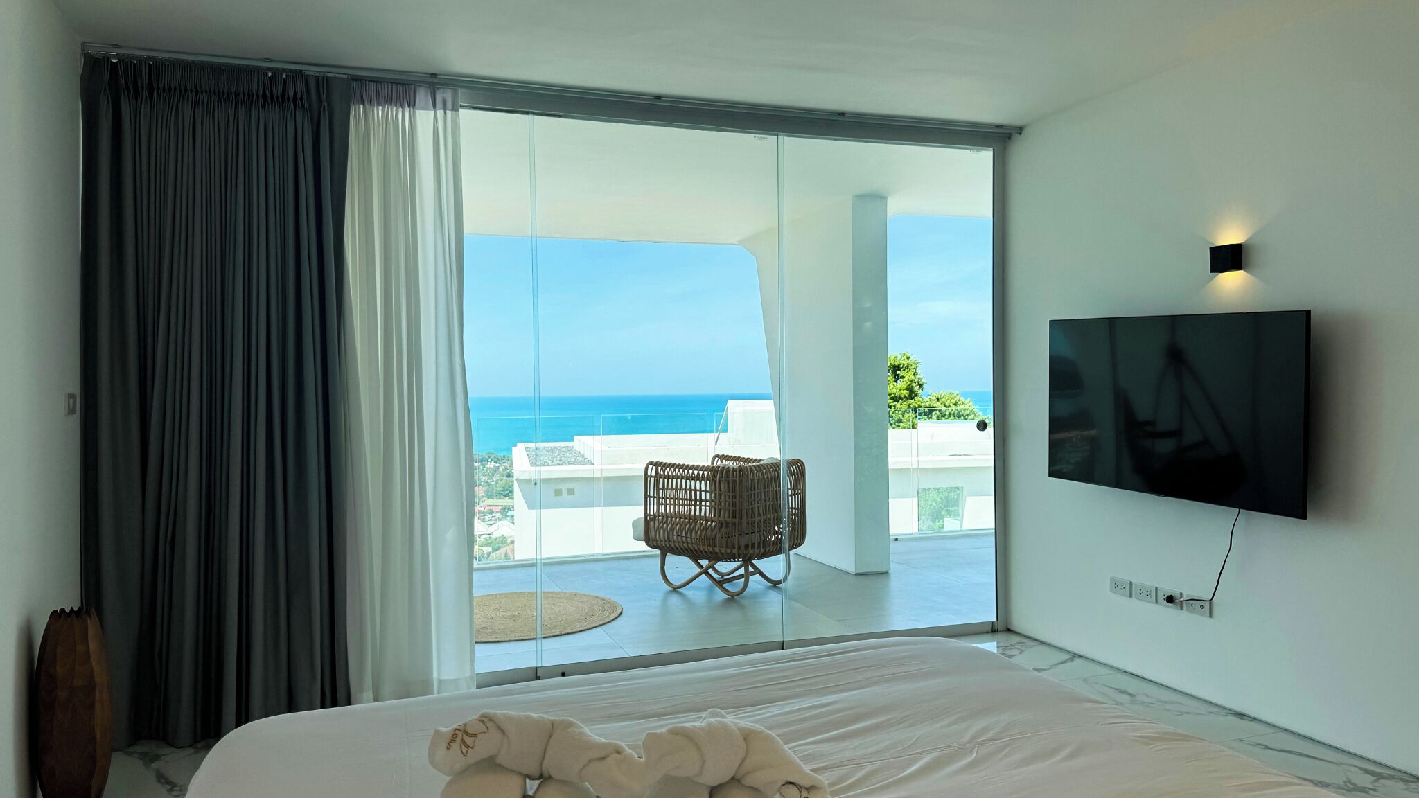 Un dormitorio con cama, televisor y vista al océano.