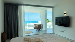 A bedroom with a bed, a TV, and a view of the ocean. - Golden Lotus Villas (Koh Samui)