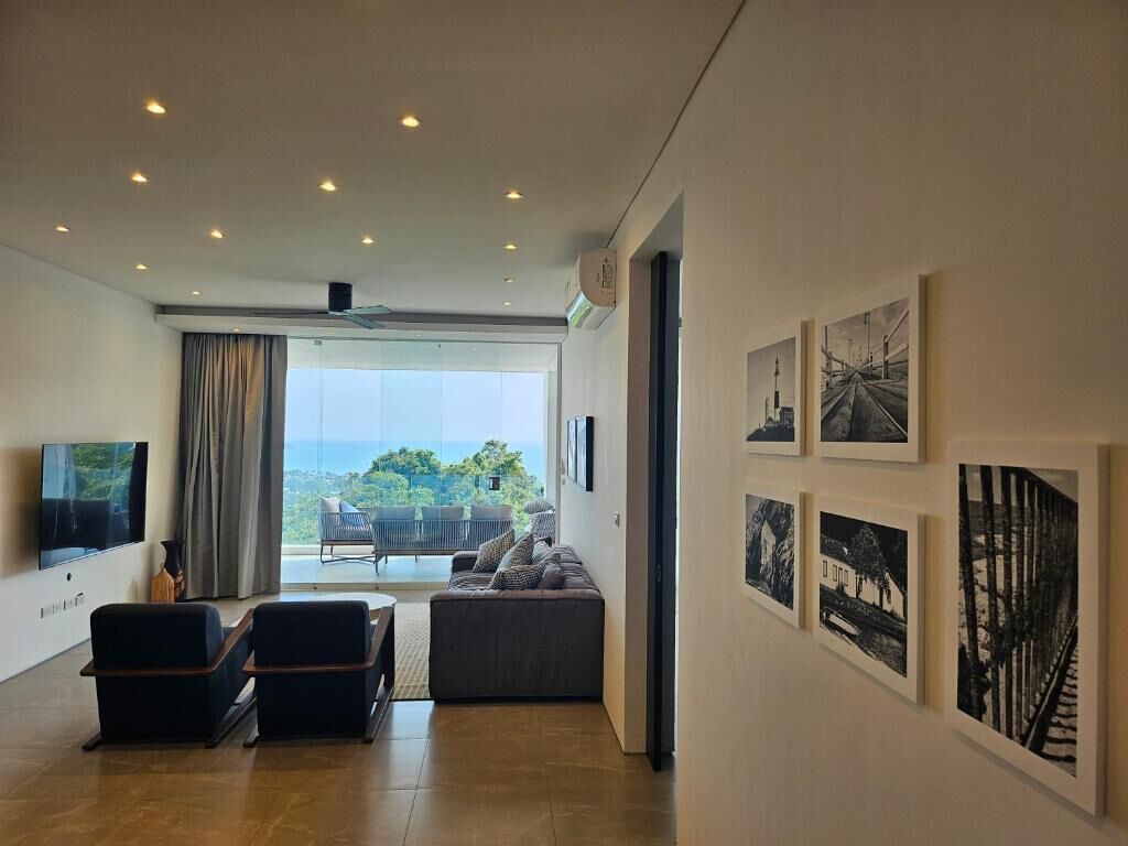 Una sala de estar moderna con un ventanal grande, un televisor de pantalla plana, un sofá y obras de arte en las paredes.