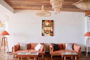 A room with two sofas, a coffee table, and a painting on the wall. - Coast 67 Boutique Hotel (Ahangama)