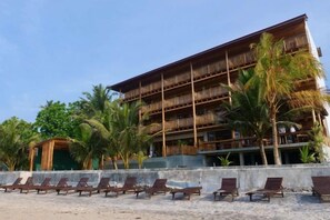 A multi-story building with a wooden facade, a balcony on the upper floor, and a row of sun loungers in front. - Coast 67 Boutique Hotel (Ahangama)