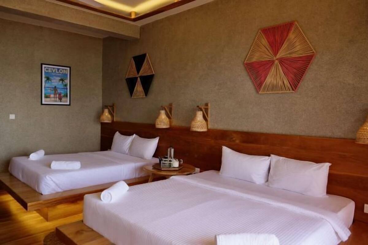 A hotel room with two beds, a wooden headboard, a wall with geometric wall art, and a framed picture.