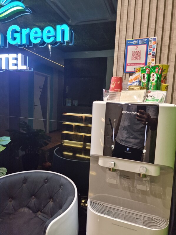 A hotel reception area with a water dispenser, a neon sign reading "Green HOTEL", and a QR code for services. - Laman Green Hotel Seksyen 7 (Shah Alam)