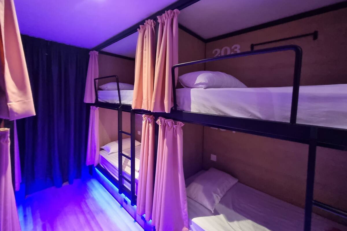 A bunk bed room with curtains, a number on the wall, and a ceiling light.