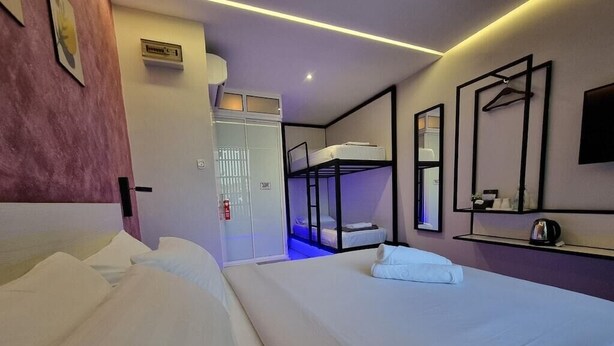 Une chambre d’hôtel équipée d’un lit superposé, d’un lit simple, d’une armoire, d’un miroir et d’une étagère avec des articles de toilette.