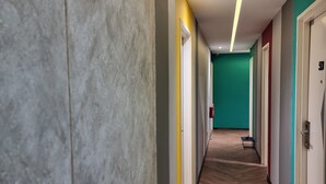 Un couloir d’hôtel moderne avec un plancher en bois, des murs aux couleurs vives et des portes donnant accès aux chambres.