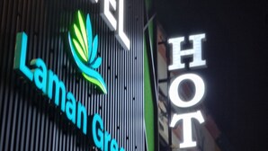 Une enseigne d’hôtel portant le nom « Laman Green Hotel » et un logo.