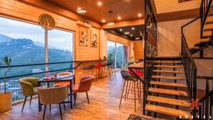 A modern interior with a wooden staircase, a dining area with chairs, and a view of the outdoors. - Zostel Kodaikanal (Vilpatti) (Kodaikanal)