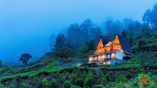 A two-story building with a steep roof, surrounded by lush greenery and misty mountains. - Zostel Kodaikanal (Vilpatti) (Kodaikanal)