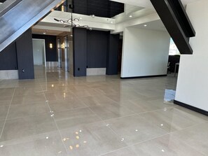 A spacious lobby with a polished tile floor, a staircase, and a modern ceiling design.