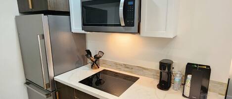 A modern kitchen with a built-in microwave, a coffee maker, and a water dispenser.