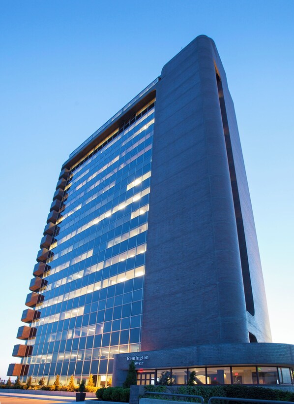 A modern high-rise building with a glass facade and a prominent cylindrical section.