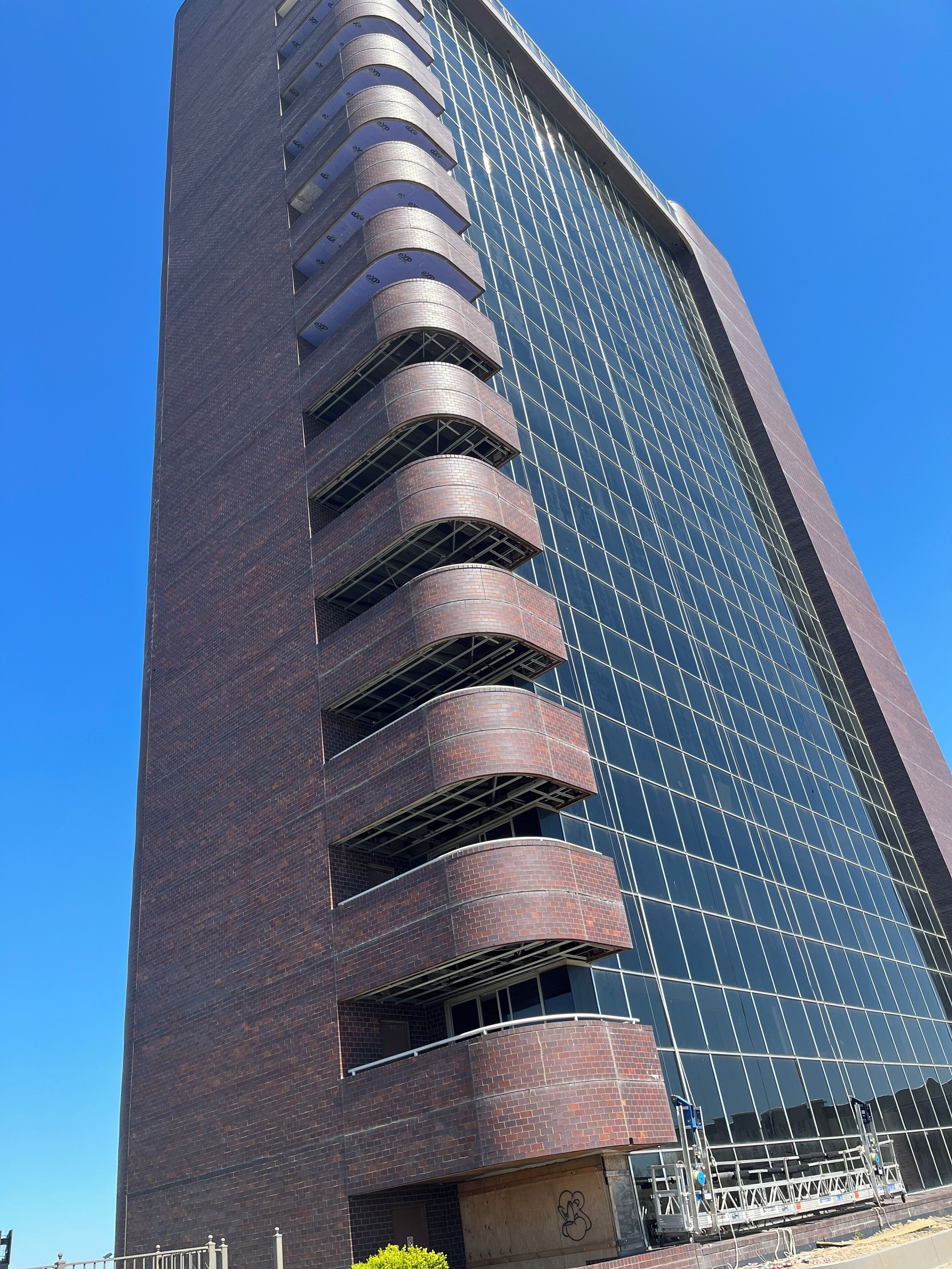 A tall building with a modern design, featuring a series of curved balconies and a large glass facade.