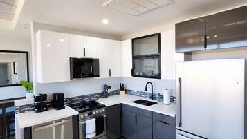 A modern kitchen with white and black cabinetry, stainless steel appliances, and a tiled backsplash.