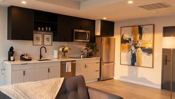 A modern kitchen with dark cabinetry, a stainless steel refrigerator, and a microwave.