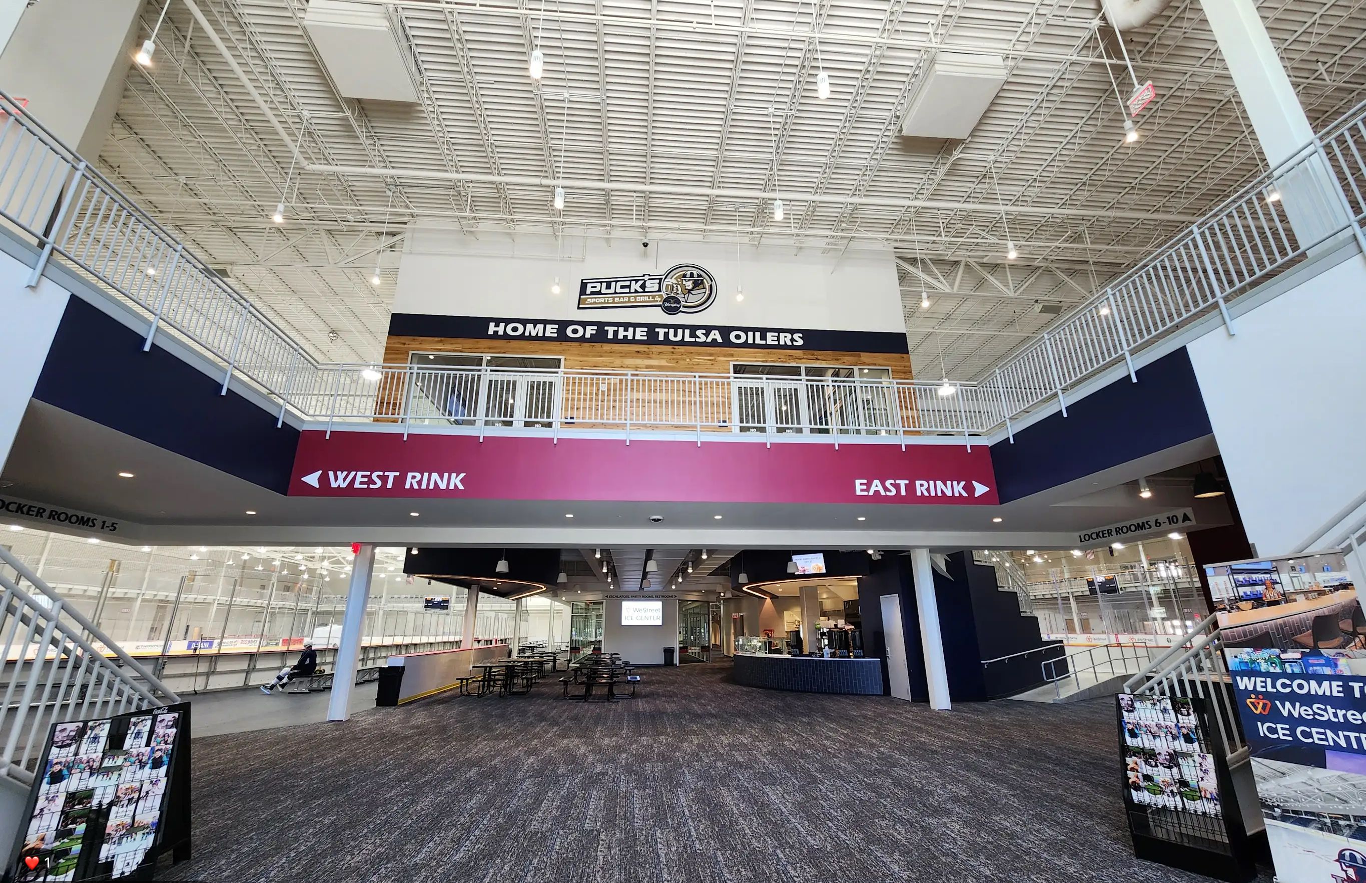 A spacious indoor area with a high ceiling, a sign reading "Home of the Tulsa Oilers," and directional signs for locker rooms.