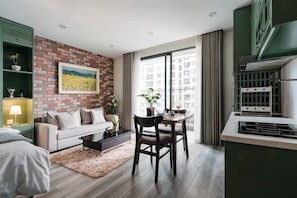 Ein modernes Wohnzimmer mit Ziegelwand, einem Essbereich mit Tisch und Stühlen sowie einer Küche mit großem Fenster.