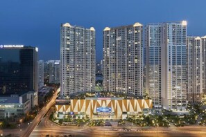 A high-rise building complex with multiple floors, a central plaza, and a large screen displaying an advertisement. - Vinhomes D'Capitale - Luxury Kane Aparment In Ha Noi (Hanoi)