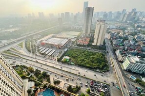A high-rise building with multiple floors, a parking area, and a road with vehicles. - Vinhomes D'Capitale - Luxury Kane Aparment In Ha Noi (Hanoi)
