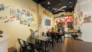 A restaurant interior with tables and chairs, a counter, and walls decorated with travel-themed artwork and signs. - Hanoi Quarter Life Hostel (Hanoi)
