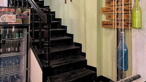 A staircase with a refrigerator stocked with beverages, a wall-mounted sign with various messages, and a display of hanging bottles. - Hanoi Quarter Life Hostel (Hanoi)