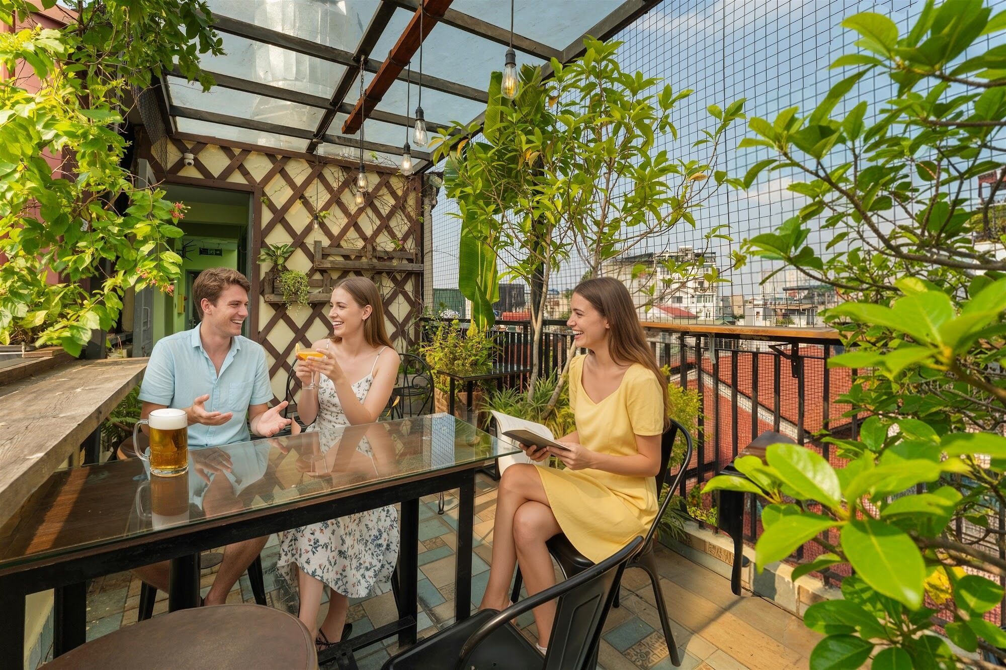 Un espace extérieur aménagé avec une table en verre, des chaises et des plantes en pot.