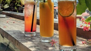 Three glasses of iced drinks with straws and lemon slices on a wooden surface. - Hanoi Quarter Life Hostel (Hanoi)