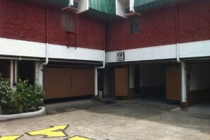 Un bâtiment à la façade en briques rouges, doté de plusieurs portes de garage et d’une aire de stationnement signalée par des flèches directionnelles.
