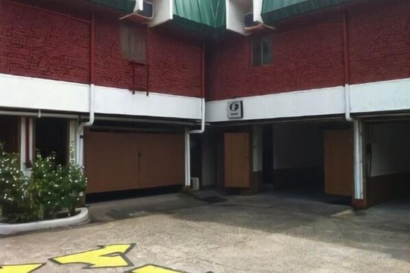A building with a red brick facade, multiple garage doors, and a parking area with directional arrows.