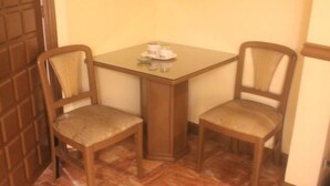 A small room with a glass-top table and two wooden chairs with cushioned seats. - Halina Drive Inn Hotel - Pasay (Pasay)