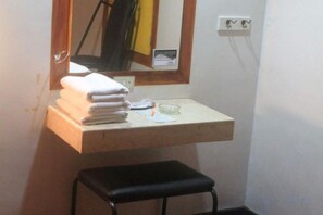 A bathroom with a sink, a mirror, a towel stack, and a black stool. - Halina Drive Inn Hotel - Pasay (Pasay)