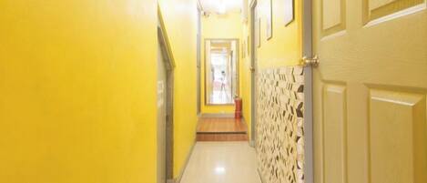 A hallway with yellow walls and a patterned wall on the right.