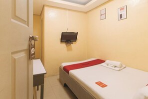 Una habitación de hotel con cama, televisor montado en la pared, una mesita y una puerta con picaporte.