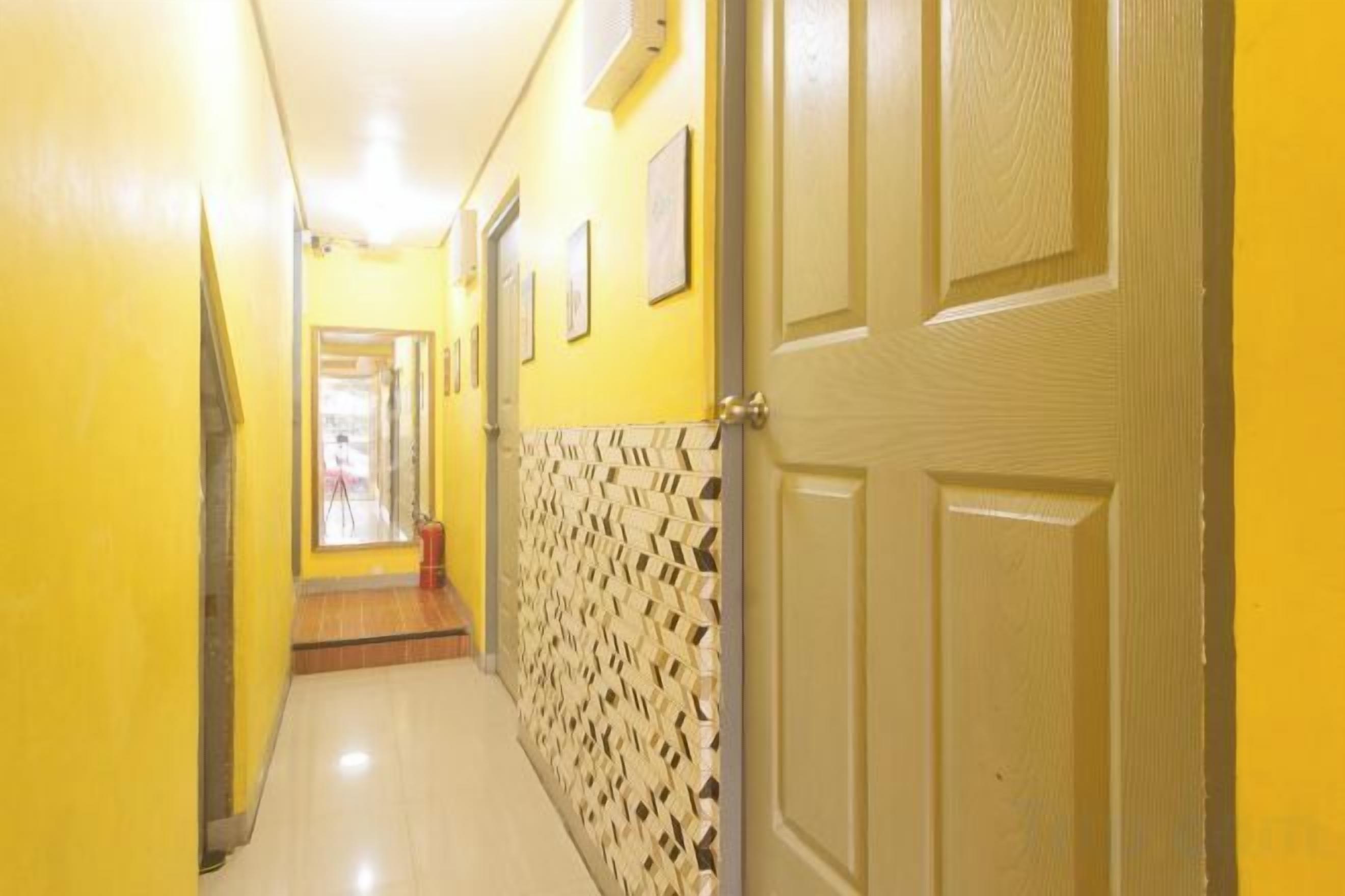 A hallway with yellow walls, a patterned wall section, and a door.