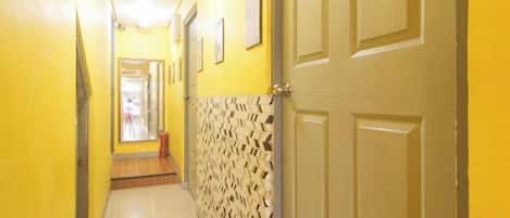 A hallway with yellow walls, a patterned wall section, and a door.