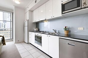 Een moderne keuken met witte kasten, een roestvrijstalen koelkast, een magnetron, een fornuis en een vaatwasser.