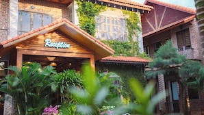 A reception area with a wooden facade, brick walls, and a tiled roof. - Tam Coc Little Charm Villa & Bungalow (Nam Hoa Lu)