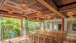A spacious indoor area with bamboo ceiling and walls, large windows offering views of greenery, and multiple seating arrangements. - Tam Coc Little Charm Villa & Bungalow (Nam Hoa Lu)