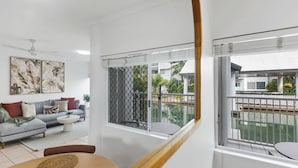 Een moderne woonkamer met een grijze bank, een bijzettafeltje en een eethoek met een houten tafel.