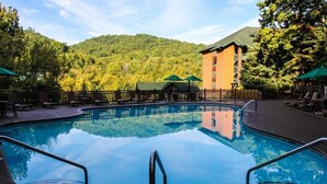 A swimming pool with a view of a forested mountain and a building in the background.
